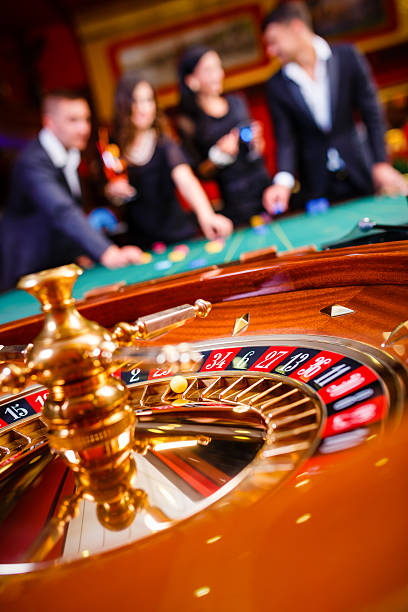 Live dealer at baccarat table holding dealing shoe with cards visible
